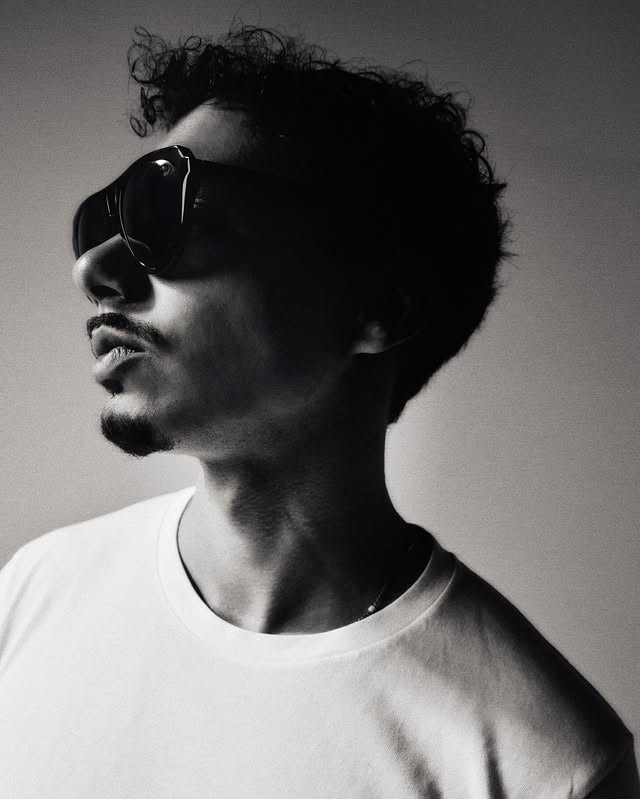 Black-and-white profile portrait of Andre Droga wearing sunglasses